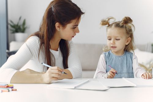 Free A mother and daughter enjoy quality time together coloring at a table indoors. Stock Photo