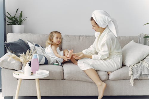 Woman in White Robe Sitting on Couch with Her Daughter