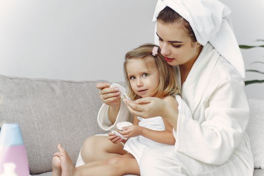 A mother and daughter enjoy bonding time at home, wearing cozy bathrobes and sharing affection.