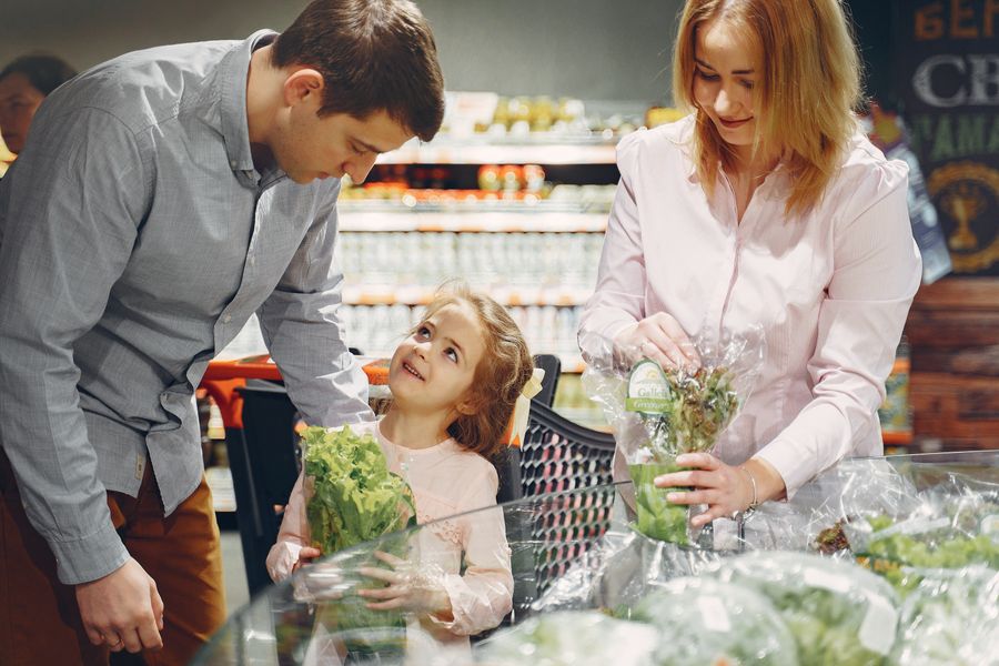 A family enjoys shopping for fresh produce together in a supermarket, smiling and bonding.