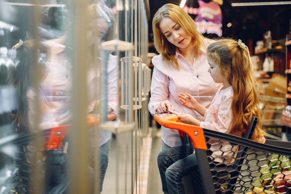 Mãe e filha conferindo a lista de compras no corredor do supermercado