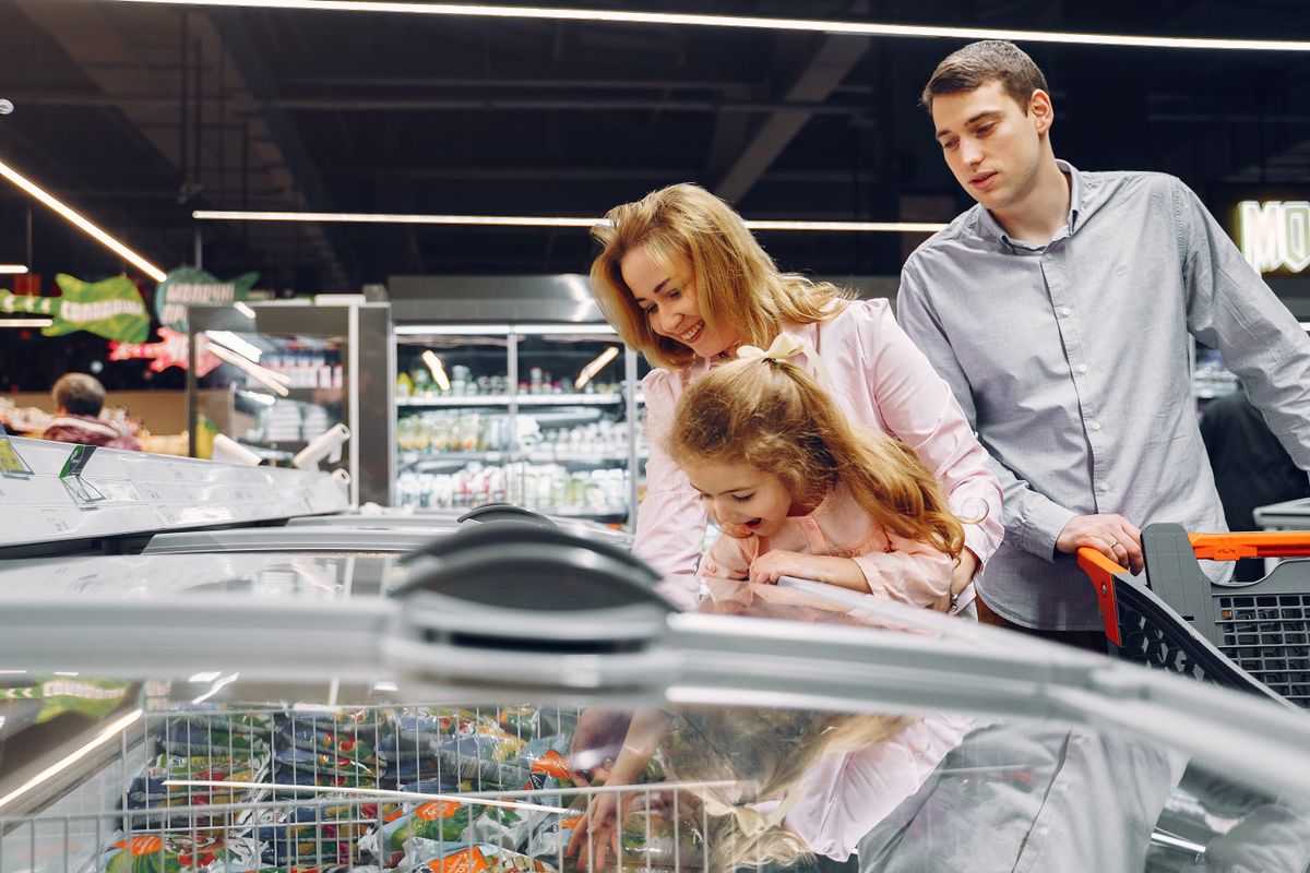 A family grocery shopping in a supermarket aisle