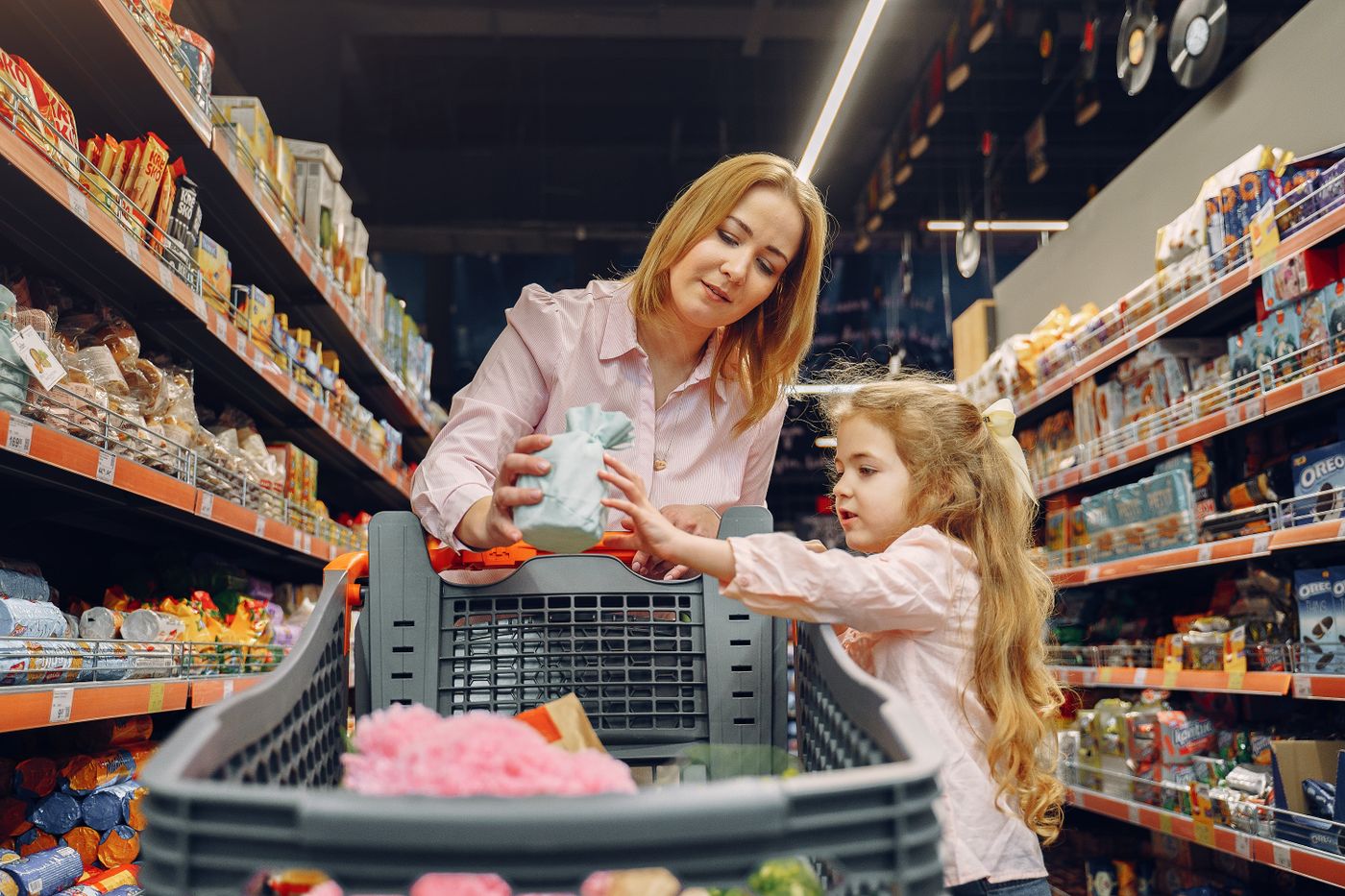 A mother and daughter shopping together in a supermarket aisle, enjoying quality time.