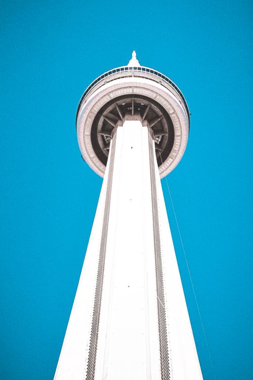 Free Stunning upward view of Toronto's iconic CN Tower set against a vivid blue sky, showcasing its modern architecture. Stock Photo