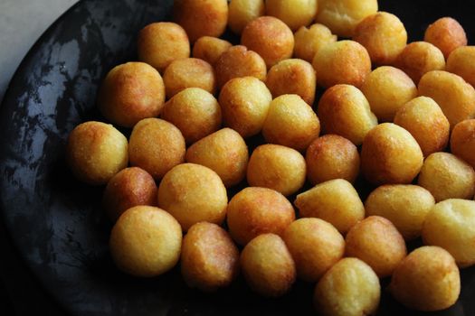 A close-up view of golden brown potato croquettes arranged on a black plate, ready to serve.