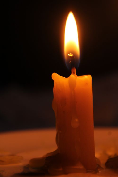 Free A close-up shot of a glowing candle flame in a dimly lit setting, creating a warm atmosphere. Stock Photo