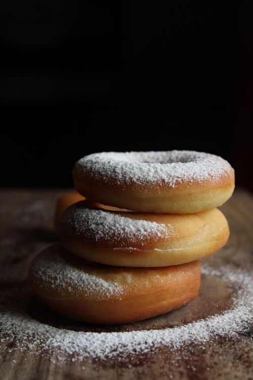 Free Close-up of three stacked powdered sugar donuts on a wooden table. Stock Photo