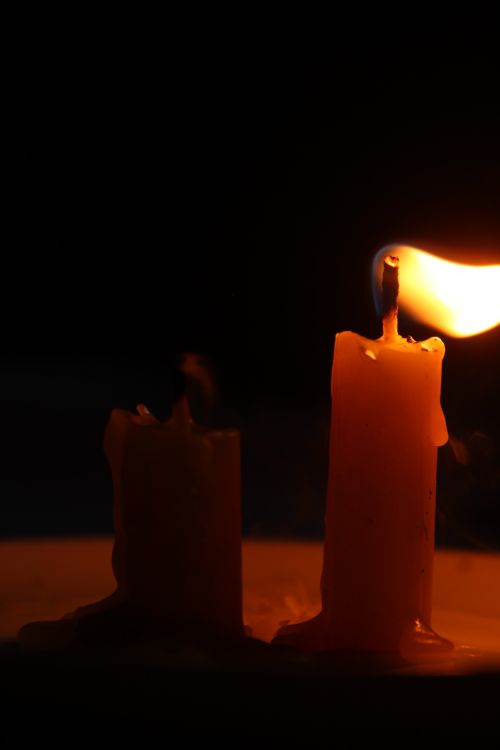 Free Warm candlelight casting serene glow in a dark setting, perfect for meditation or relaxation themes. Stock Photo