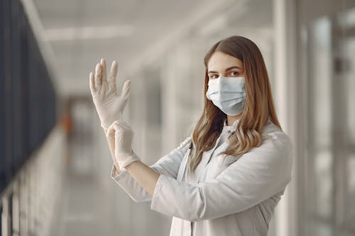 Woman in White Long Sleeve Shirt Wearing White Gloves