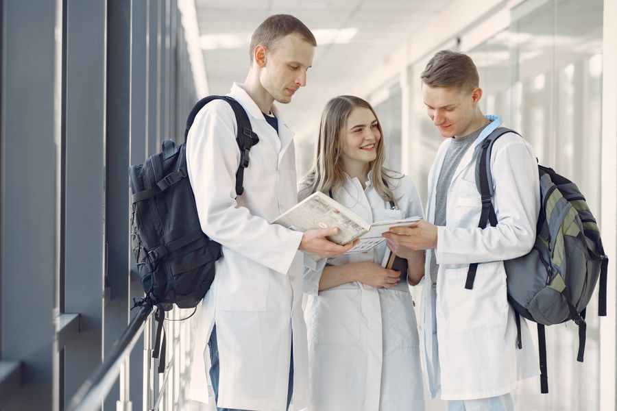 Trainee clinicians comparing notes in a hospital corridor — photo by Gustavo Fring on Pexels