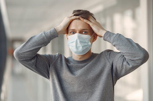 Free Man in Gray Long Sleeved Shirt Covering His Face With White Face Mask Stock Photo