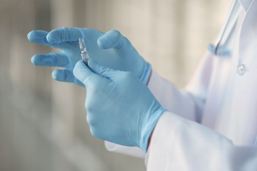 Free Close-up of a healthcare professional in gloves holding a glass vaccine ampoule. Stock Photo