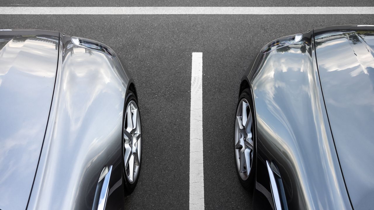 Zwei silberne Pkw stehen symmetrisch auf einem Parkplatz.