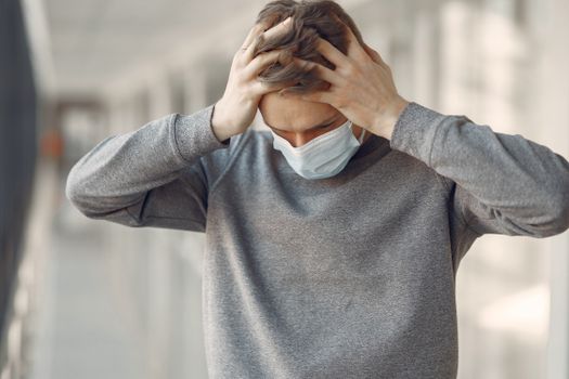 Adult male wearing a face mask, appearing stressed and worried while standing indoors.