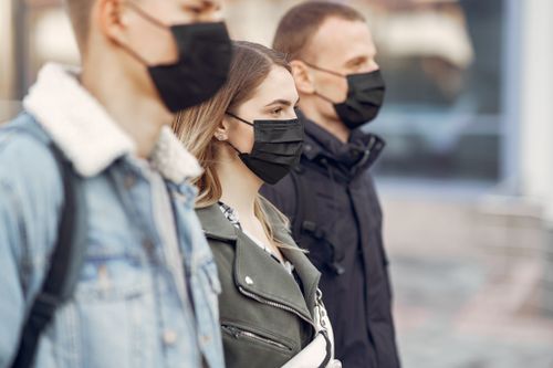 Free Group of adults wearing face masks outdoors showcasing COVID-19 prevention measures. Stock Photo