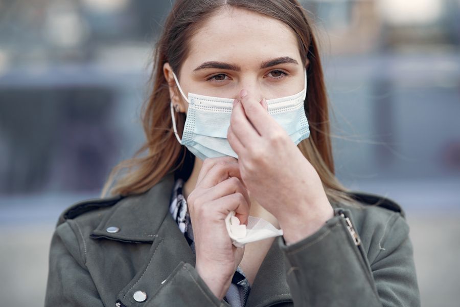 A person adjusting a protective N95-style face mask outdoors