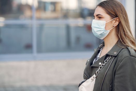 Side profile of a woman in a face mask walking outdoors on a city street.