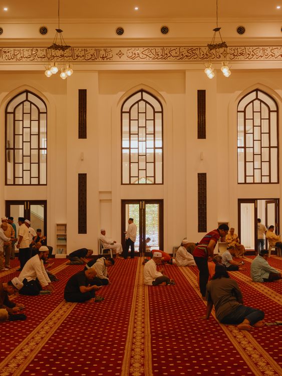 Jemaah berkumpul di interior sebuah masjid dengan arsitektur Islam yang indah