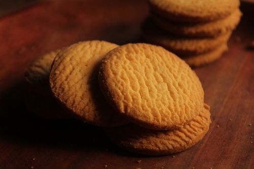 Free Delicious golden butter cookies stacked on a wooden board, perfect for snacking. Stock Photo