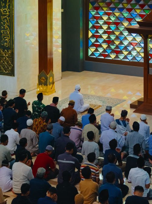 Free A group of men in prayer at a mosque in Jawa Barat, Indonesia. The colorful stained glass adds a vibrant touch to the spiritual scene. Stock Photo