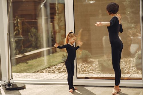 Free A mother and daughter practice ballet in matching leotards indoors, showcasing bonding and grace. Stock Photo