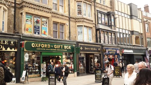 Free Lively street view of Oxford shops with people walking and browsing gifts in historic city center. Stock Photo