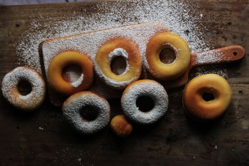 Free Delicious freshly baked donuts topped with powdered sugar on a rustic wooden board. Stock Photo