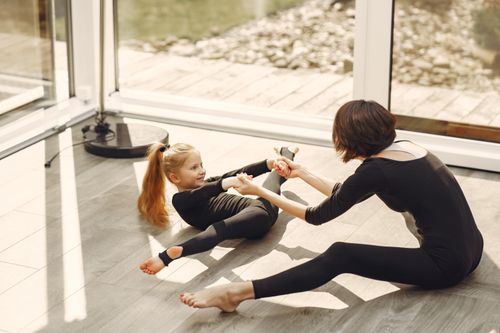 Free Mother and daughter bonding through indoor gymnastics and stretching exercises. Stock Photo
