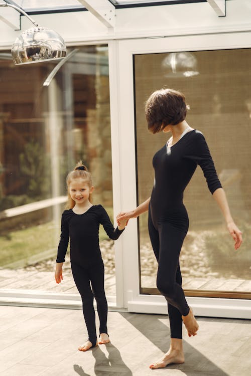 Woman and Little Girl in Black Long Sleeve Shirt and Black Pants Standing Beside Glass Wall