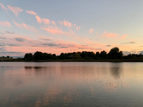 Free Tranquil lake view with stunning pink clouds during sunset, reflecting over serene waters. Stock Photo
