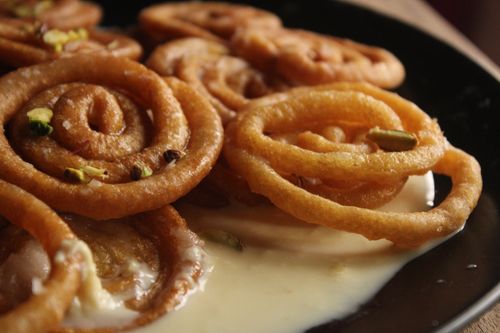 Free Mouth-watering Indian Jalebi dessert garnished with pistachios on a black plate. Stock Photo