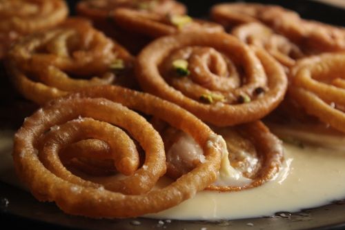 Free Delicious crispy jalebi with pistachios in creamy sauce, close-up view. Stock Photo