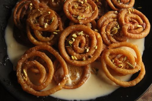Free Close-up of Indian jalebi dessert covered with nuts in a creamy sauce. Stock Photo
