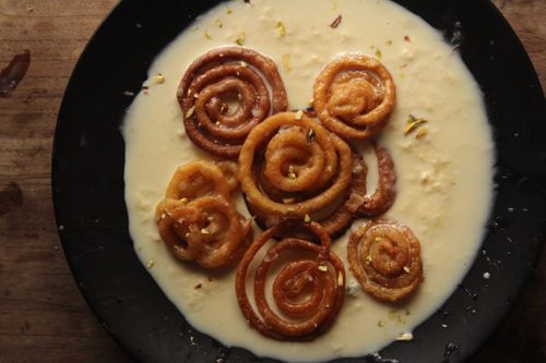 Free Tantalizing swirls of jalebi with rich, creamy rabri on a dark plate. Stock Photo