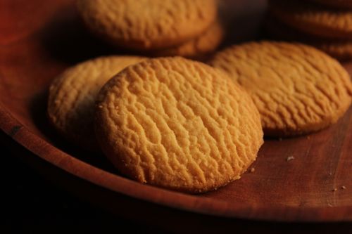 Free Close-up of golden cookies on a wooden plate, perfect for snack inspiration. Stock Photo