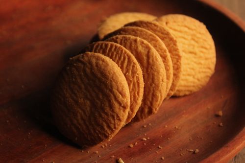 Free Delicious golden brown biscuits arranged neatly on a rustic wooden plate. Stock Photo