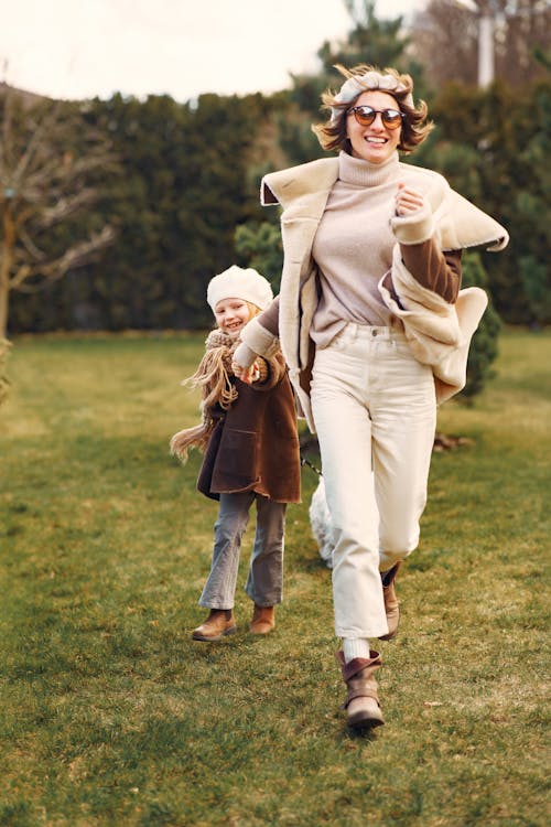 Free Woman and Little Girl Running on Green Grass Stock Photo