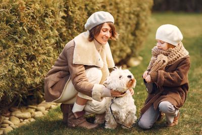 Family with small white dog in a park, everyone laughing