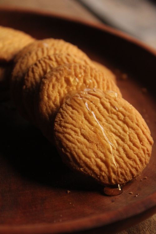 Free Close-up of honey-glazed biscuits on a wooden plate, warm lighting. Stock Photo