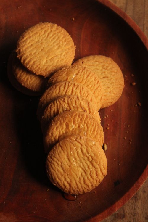 Free Stack of golden biscuits on a rustic wooden plate, natural light. Stock Photo