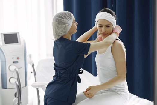 A nurse helping a patient with a head wrap in a modern healthcare clinic.