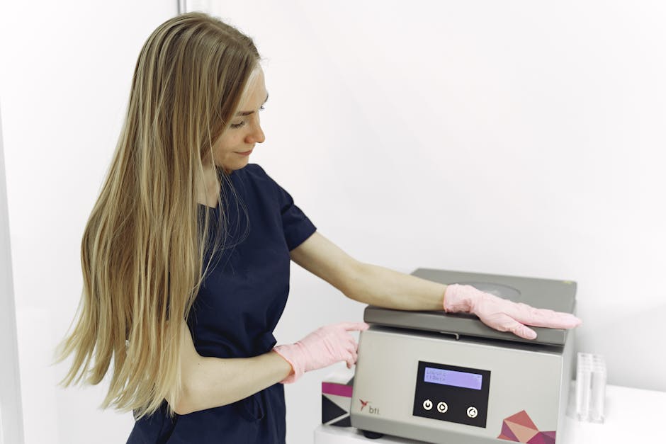 Female medical professional operating laboratory equipment indoors, wearing pink gloves.