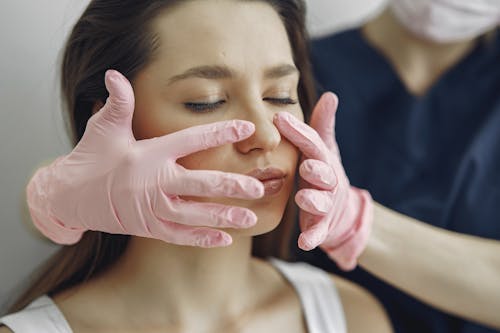 Woman in White Tank Top Getting a Face Treatment