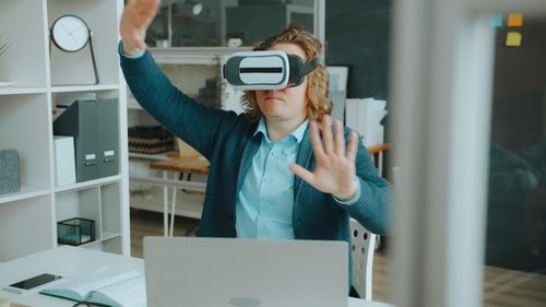 Free An adult using VR headset in a modern office environment emphasizing technology. Stock Photo
