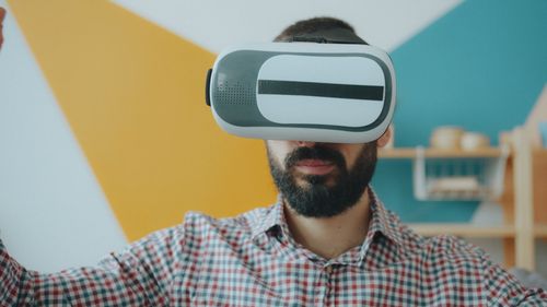 Free Man wearing VR headset in colorful room, exploring technology. Stock Photo