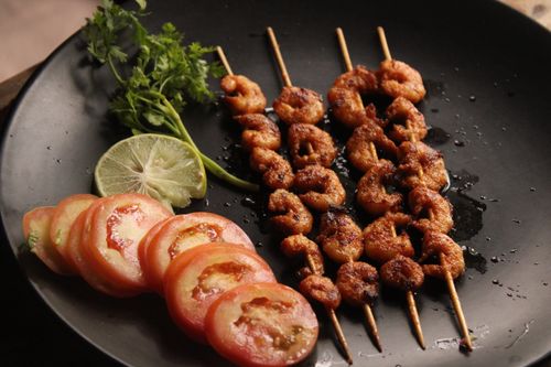 Free Delicious grilled shrimp skewers with fresh tomatoes, lime, and cilantro on a dark plate. Stock Photo