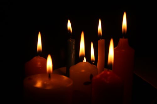 Free Close-up of lit candles casting a warm glow in darkness. Stock Photo