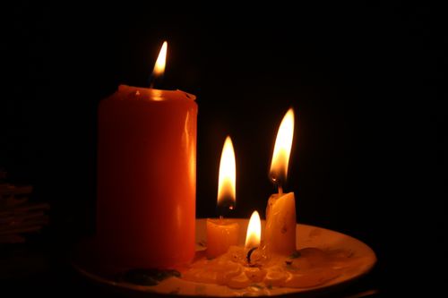 Free A cozy, close-up view of lit candles casting a warm glow in a dark setting. Stock Photo