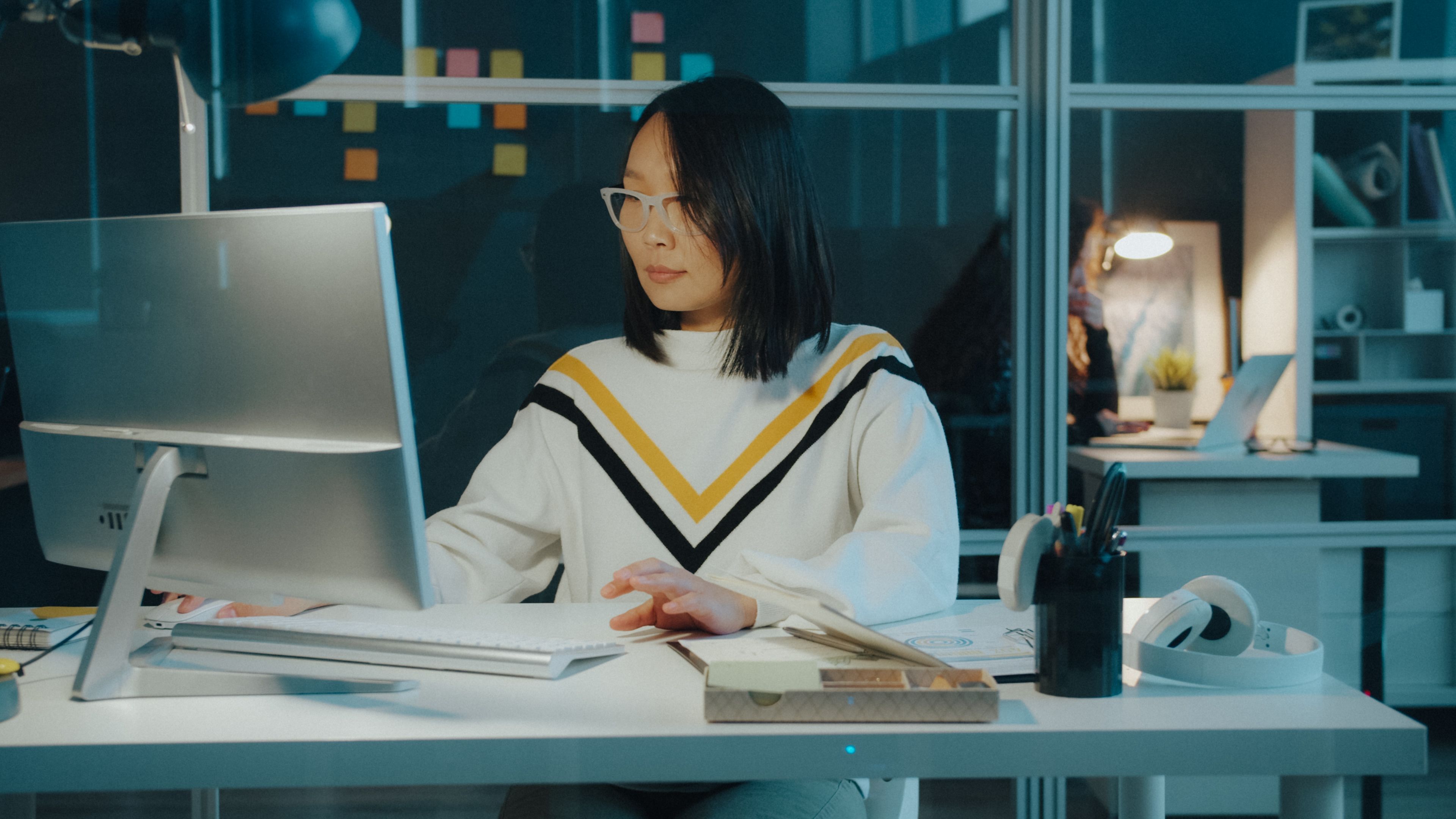 modern open plan office worker focused on monitor with headphones