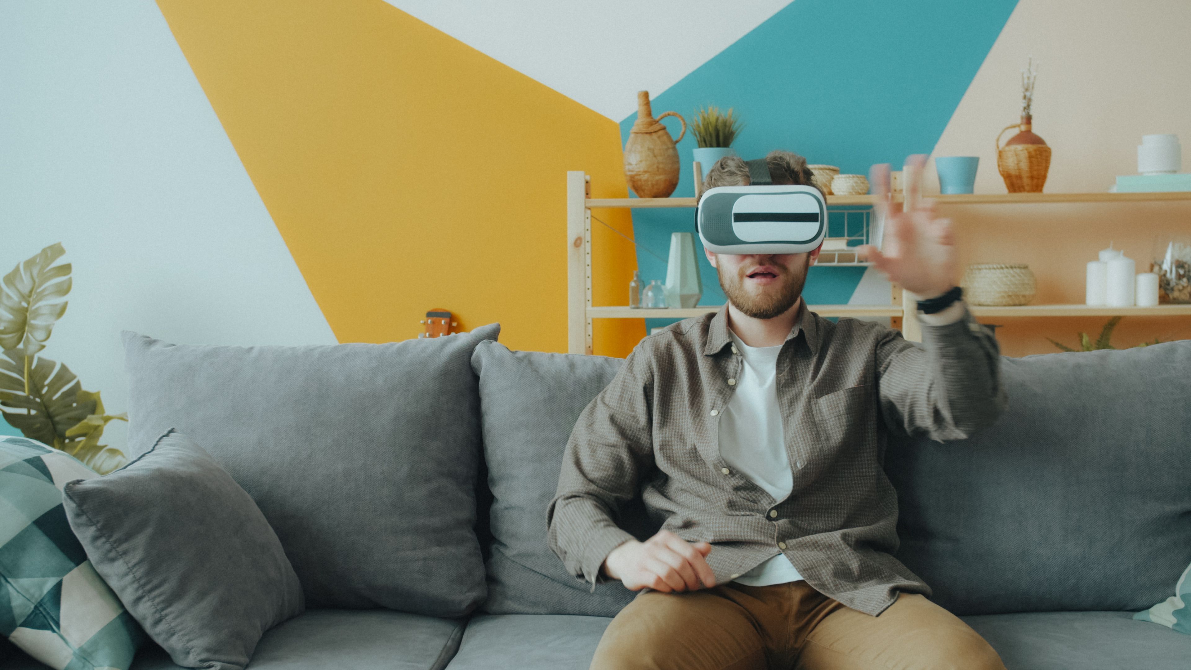 A man with virtual reality headset explores an interactive world indoors.